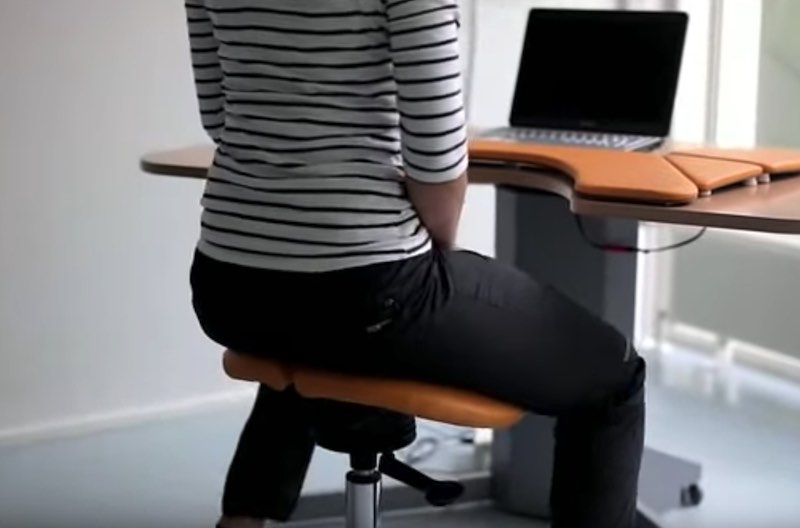 Woman sitting on a saddle chair at desk