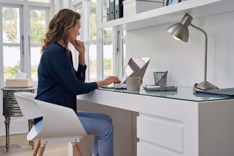 Blonde Lady working from home at a white minimal office desk