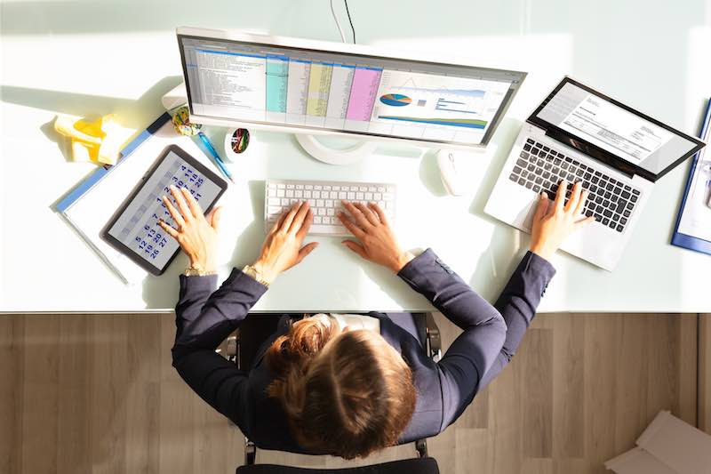 Lady multitasking on a desktop computer, on a tablet and on laptop