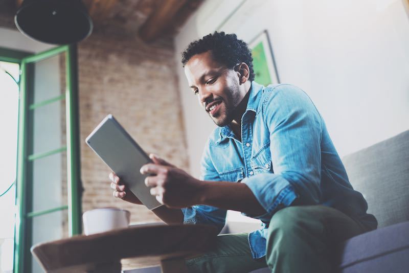 african-american man sitting on a couch using his tablet at home