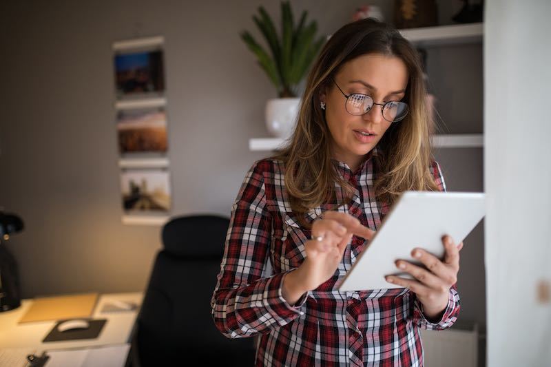 young lady wearing glasses using her tablet in her home office